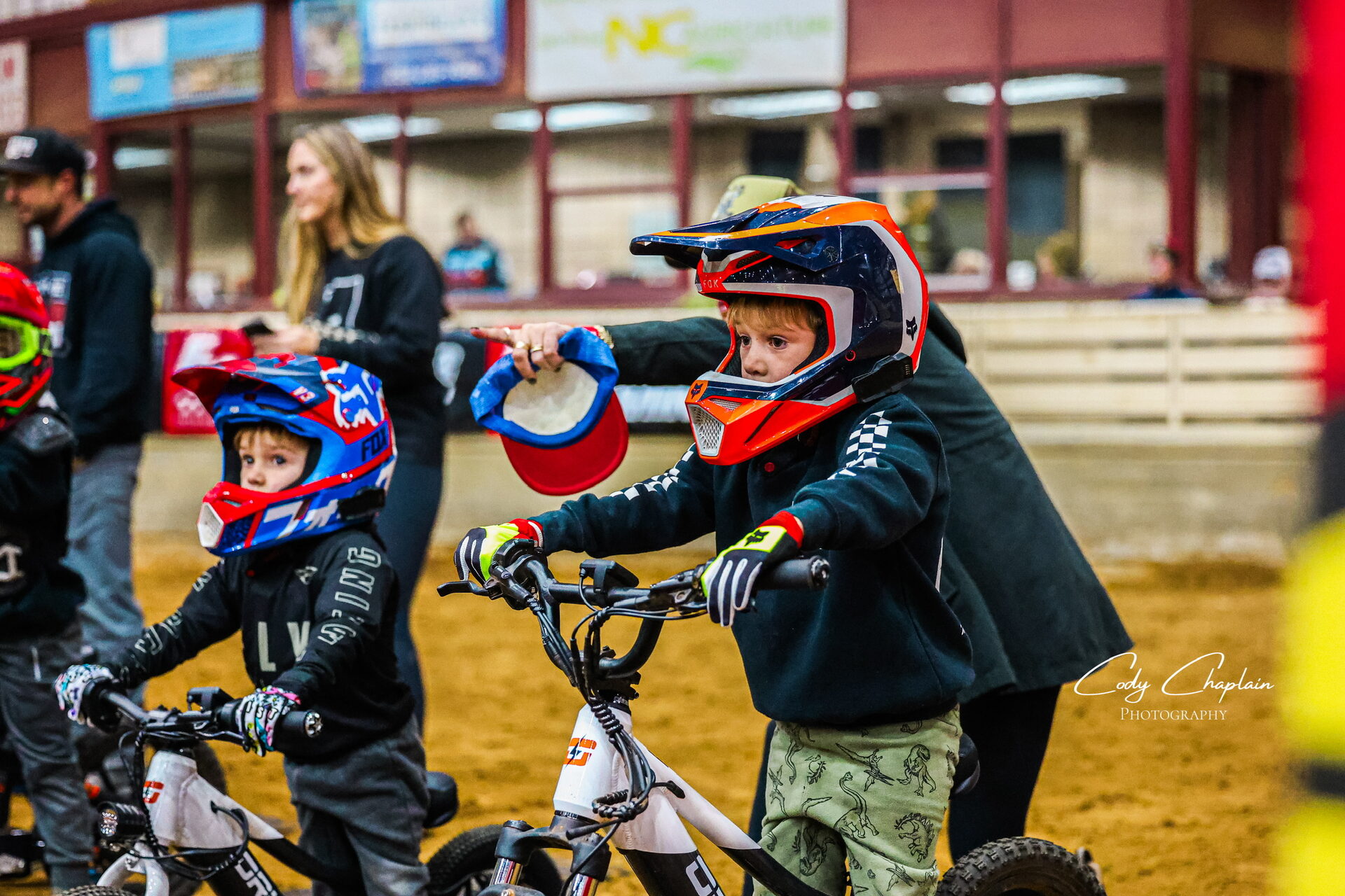 A parent helping young riders gear up at the gate