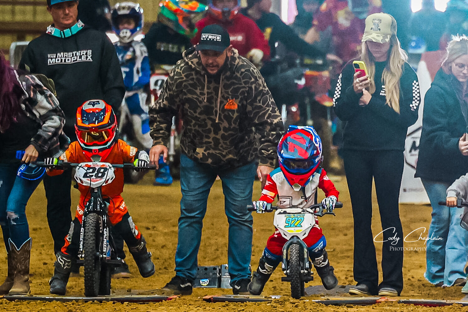 A father lines his two young riders up on their electric balance bikes at the gate